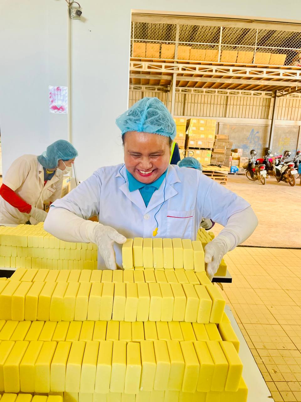 A hub soapmaker smiling as she stacks freshly pressed recycled soap bars