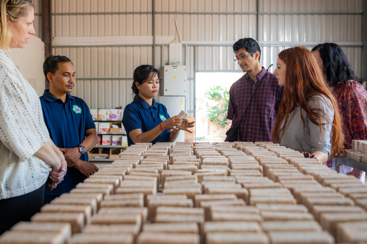 A hub team member showing visitors racks of freshly pressed recycled soap bars