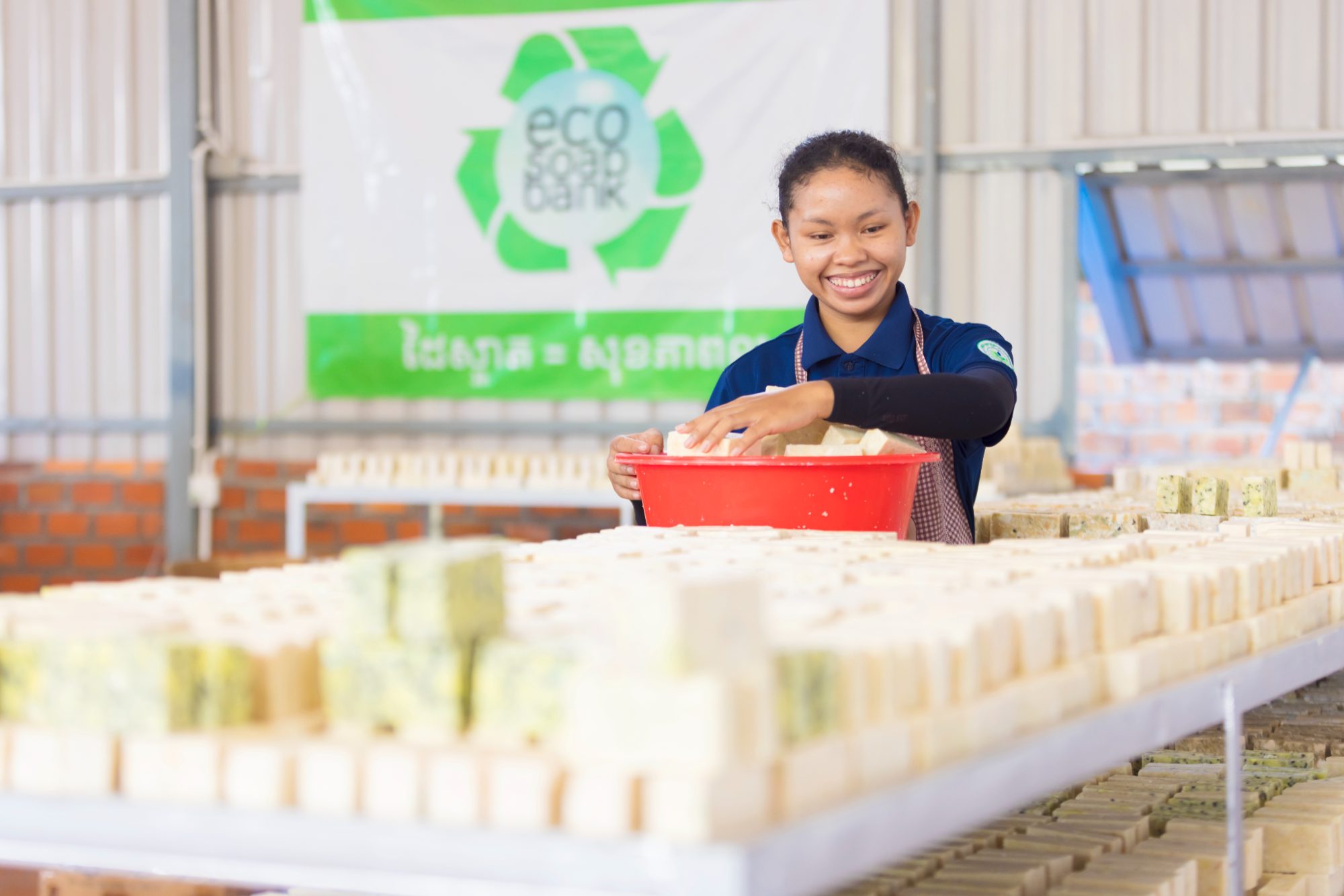 A soapmaker inspecting freshly pressed recycled soap bars