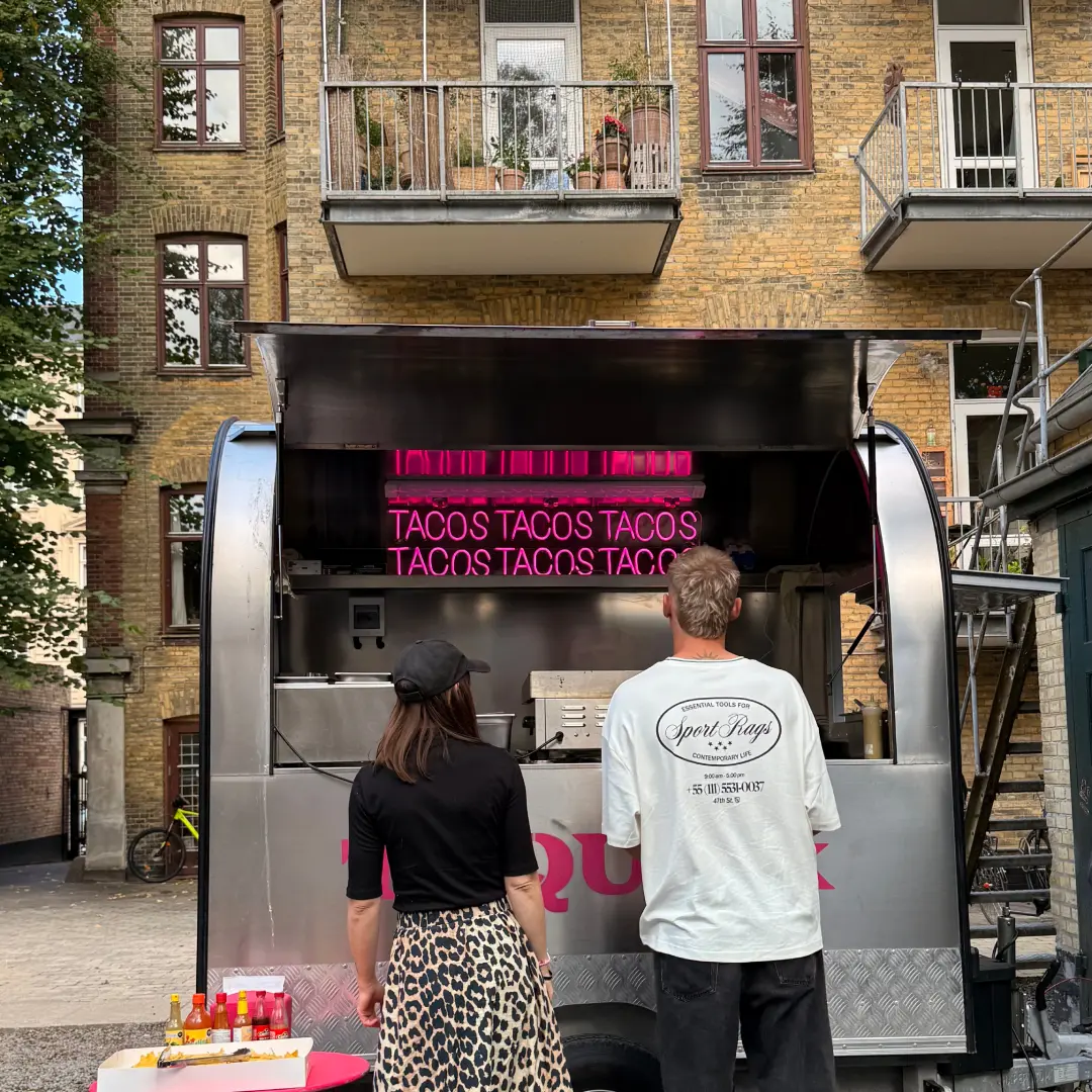 to personer foran foodtruck med flot lys og baggrund.