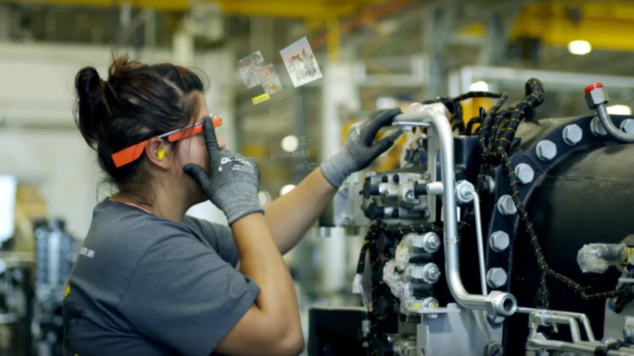 A woman operates a machine in a factory, demonstrating skill and focus in a manufacturing environment.