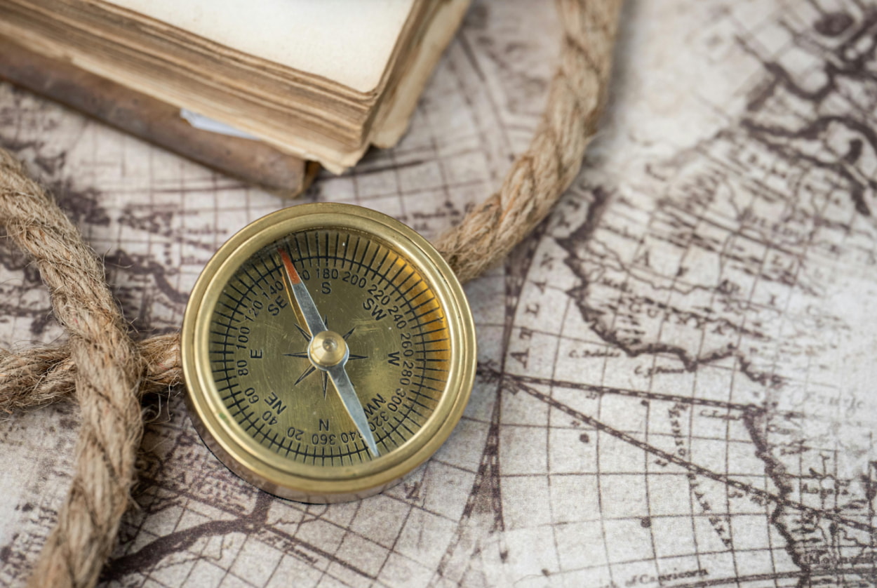 A compass and an antique book resting on a detailed map, symbolizing exploration and adventure.