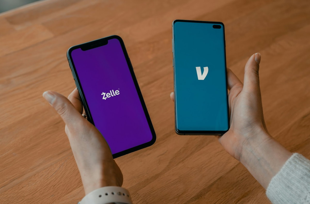 Two hands holding two smartphones displaying a prominent 'V' logo on their screens.