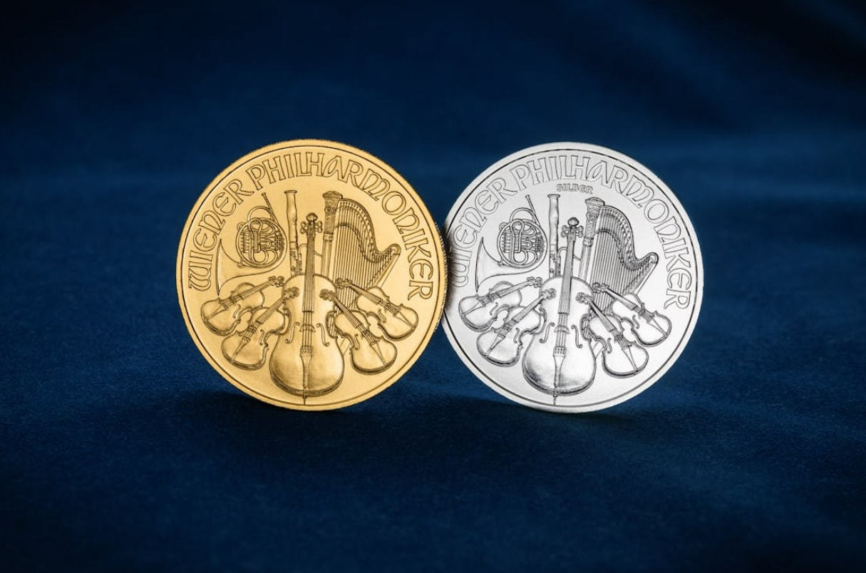 Two silver and gold coins resting on a vibrant blue background, showcasing their metallic shine and intricate designs.
