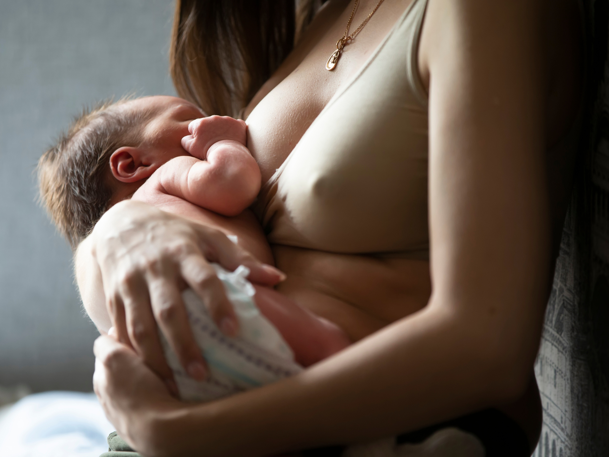 Mother breastfeeding her newborn baby in soft natural light