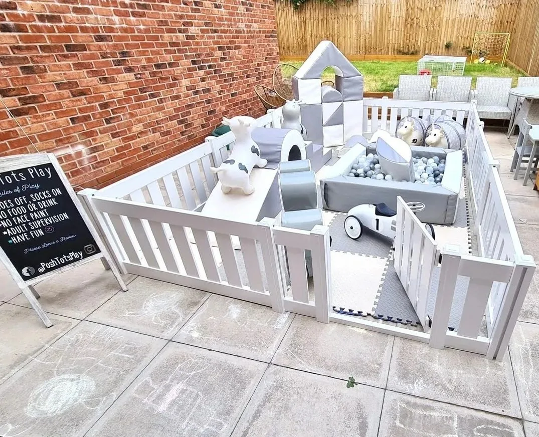 A white and grey soft play set with shapes, ride-ons and a picket fence play pen
