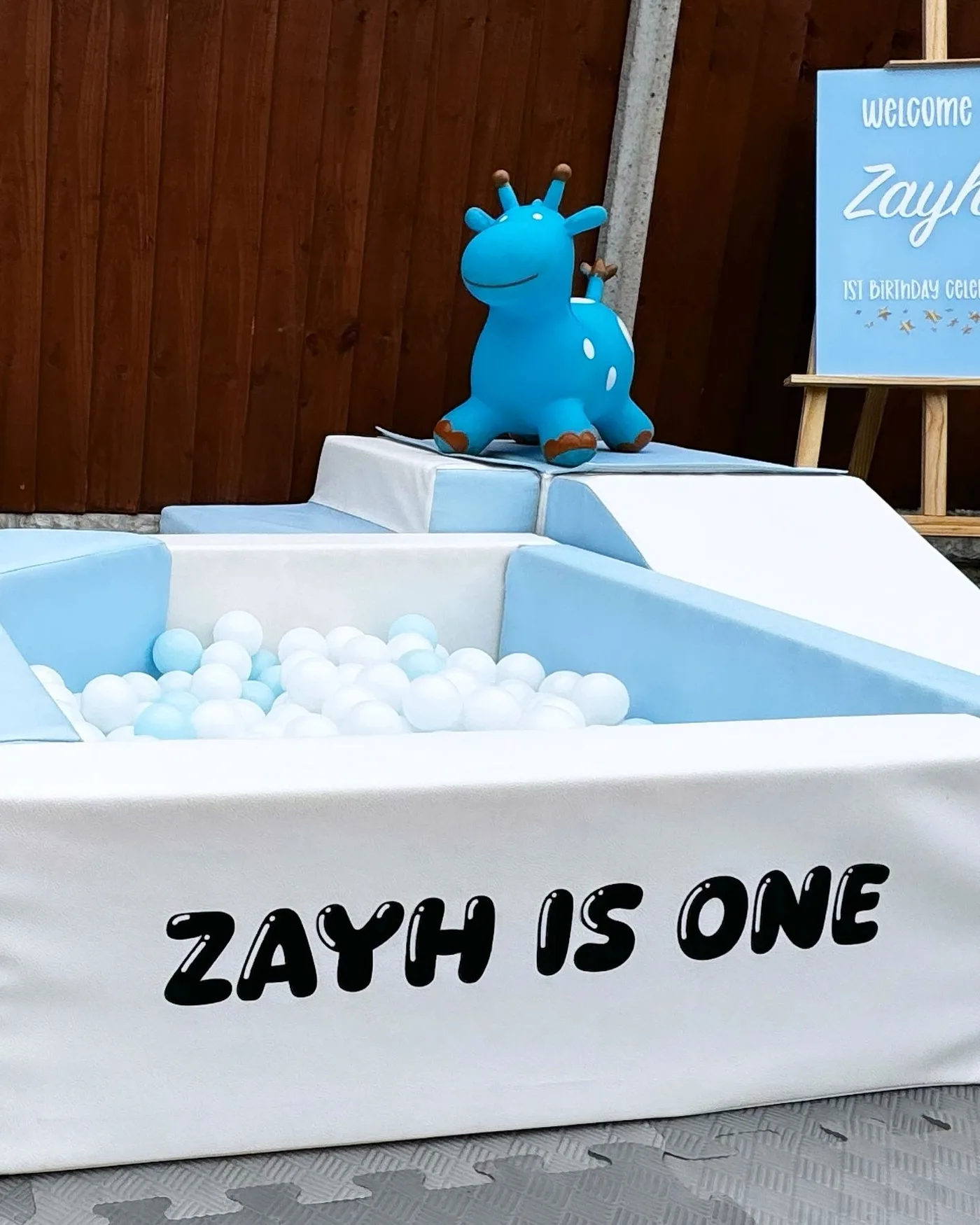 A soft play ball pit and rocking toy set up for a first birthday party