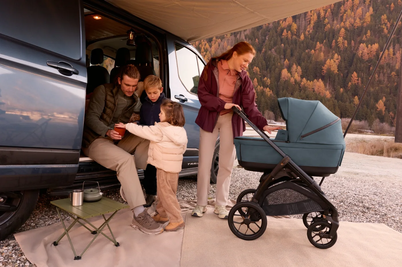 A family with an Inglesina travel system outside a campervan on an autumn day in the mountains
