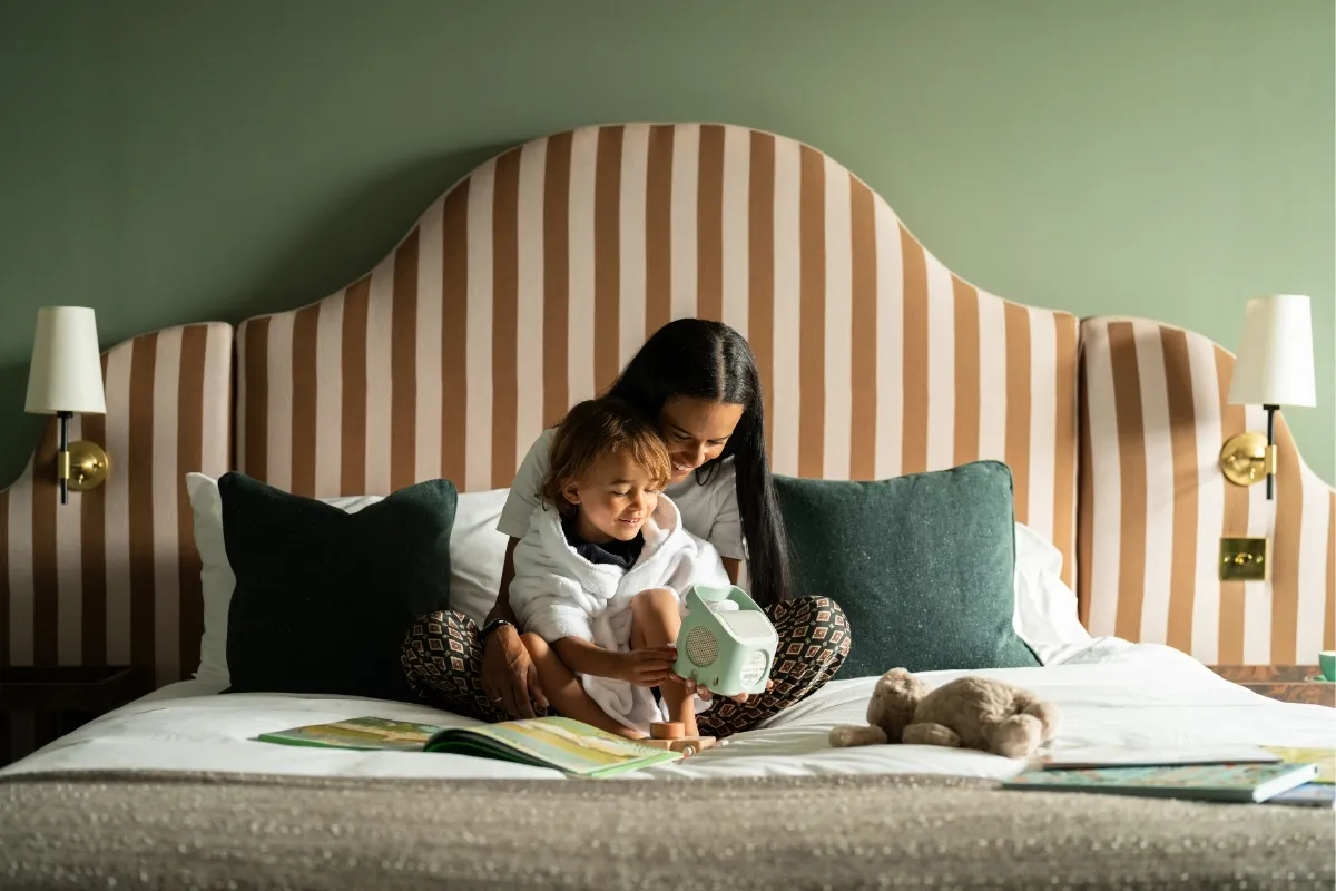 A mum reading with her toddler on a bed in a family room at The Ickworth
