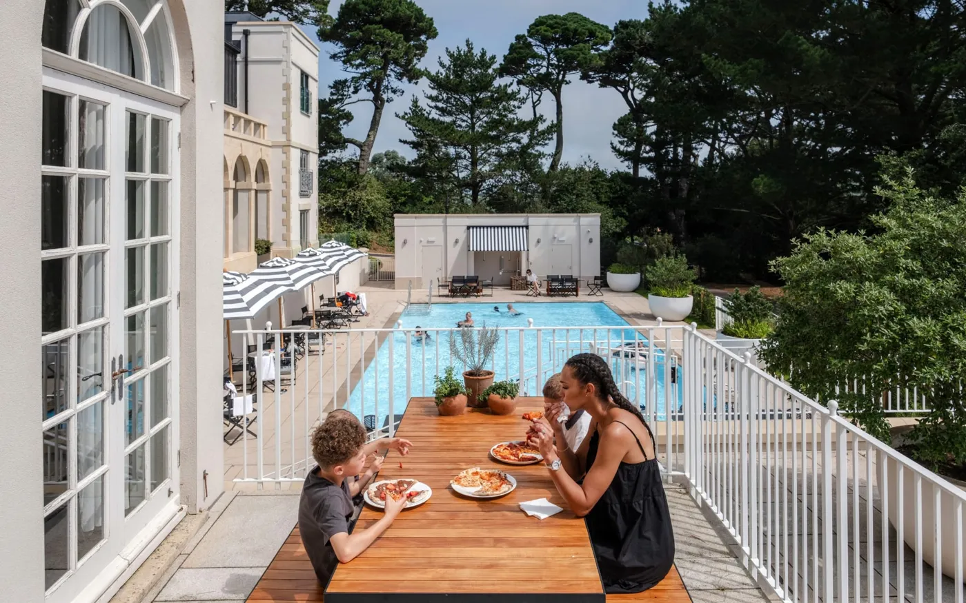 A family eating on the terrace beside the pool at Fowey Hall in Cornwall