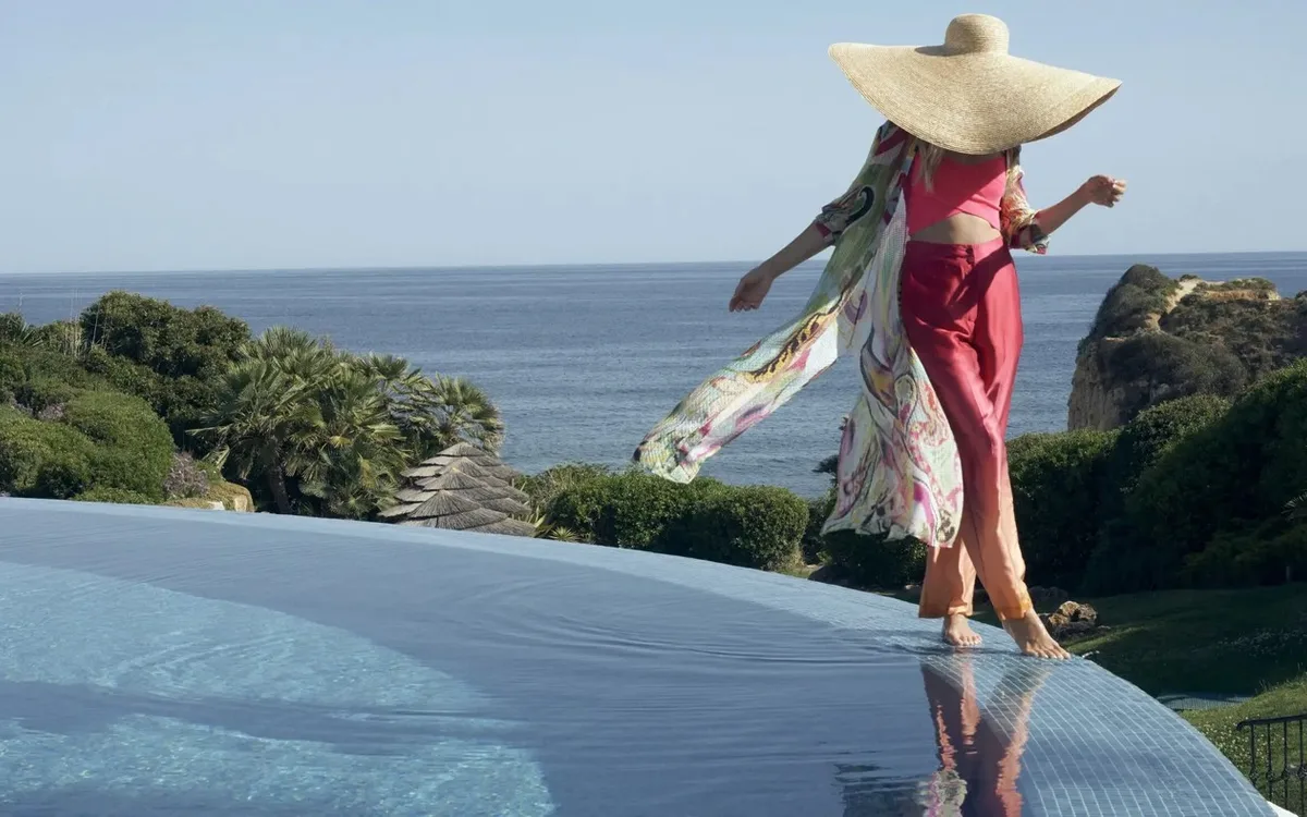 A woman in a sun hat by the infinity pool at Vila Vita Parc overlooking the sea