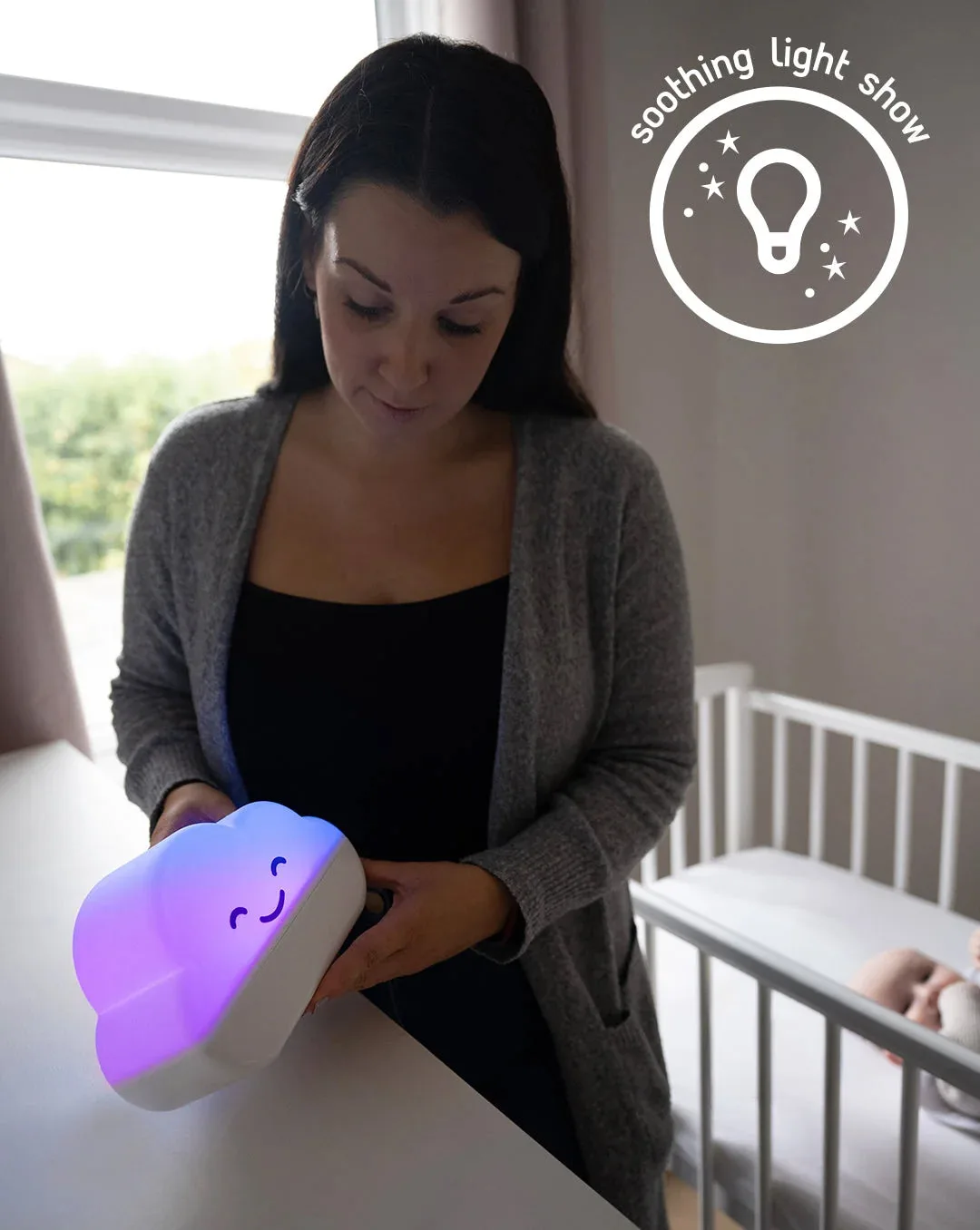A mum holding the Sweet Dreamers Misty the Cloud night light glowing purple in a nursery