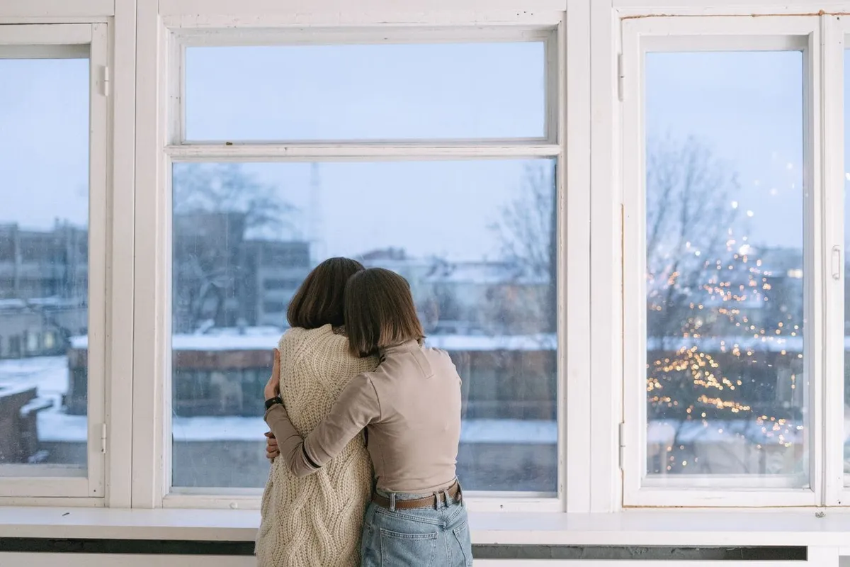 Two people hugging by a window