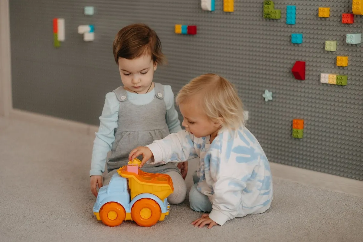 Two toddlers playing with a toy truck at nursery