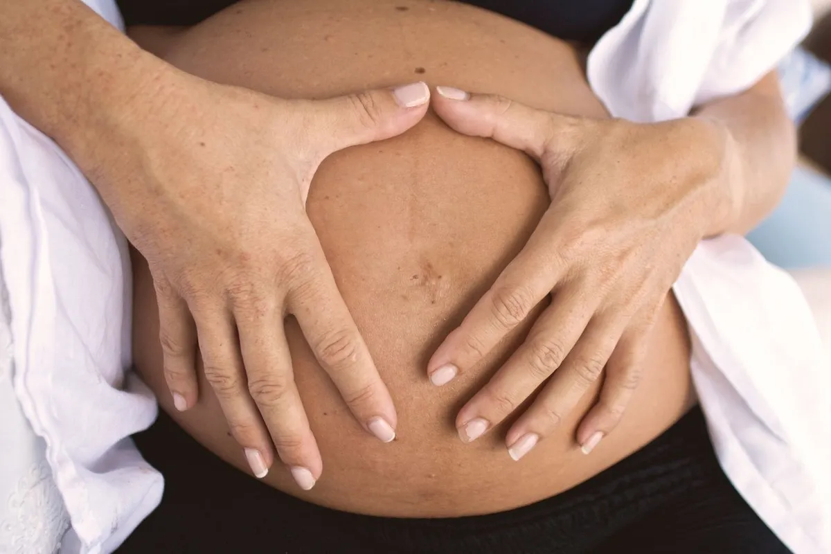 Hands making a heart shape on a pregnant bump