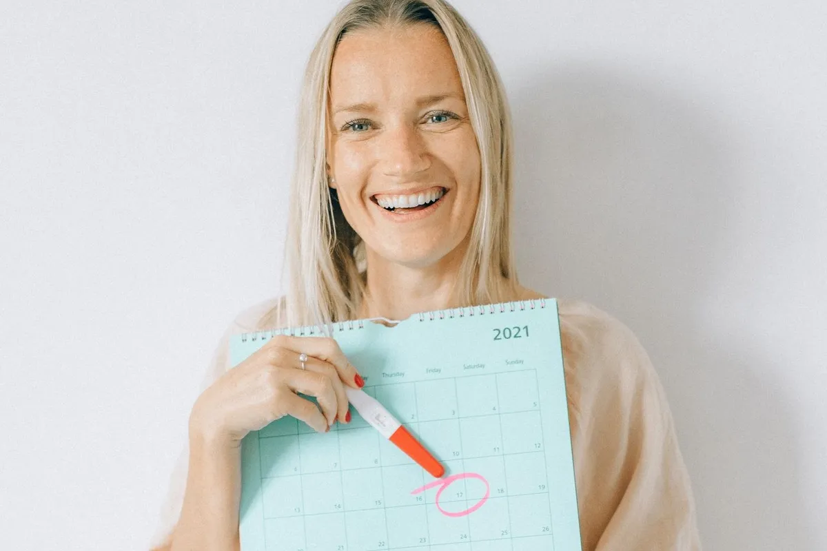 A woman holding a calendar with a date circled