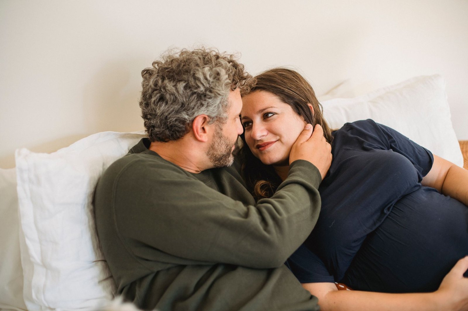 A pregnant woman and her partner lying together, laughing