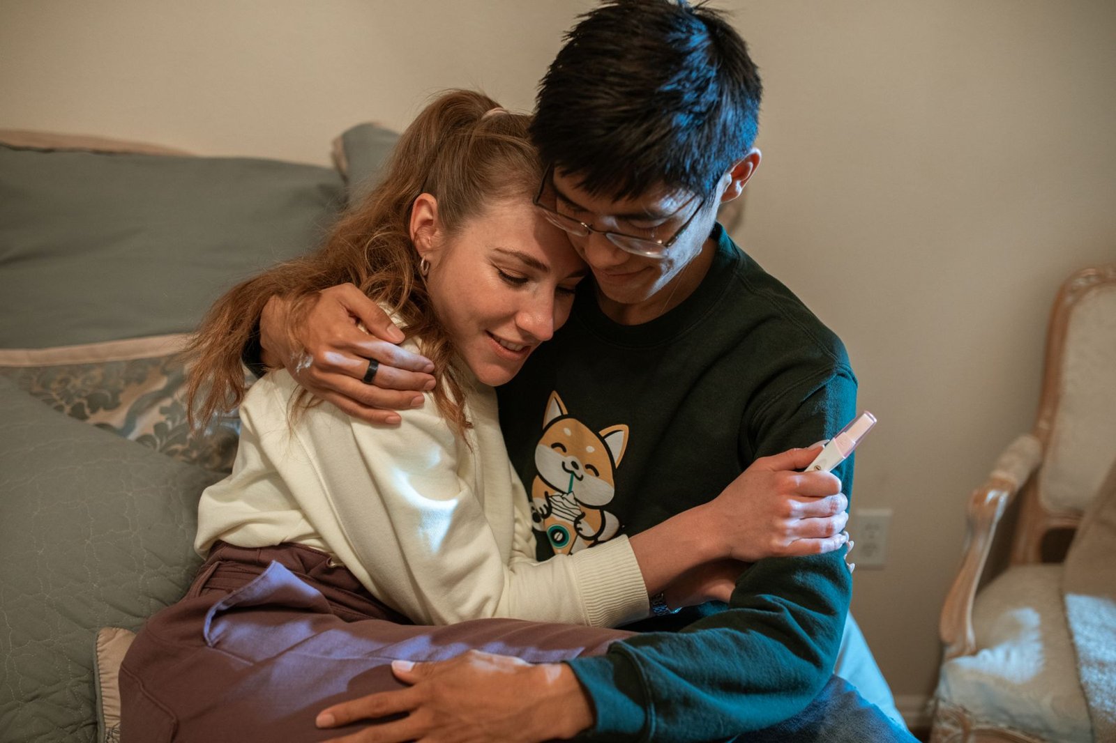 A happy couple hugging while holding a positive pregnancy test