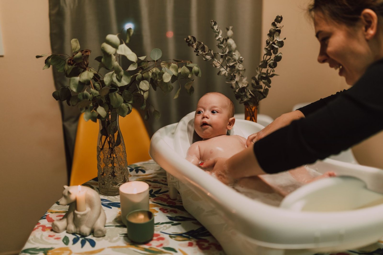 Mum gently bathing her baby in a small baby bath
