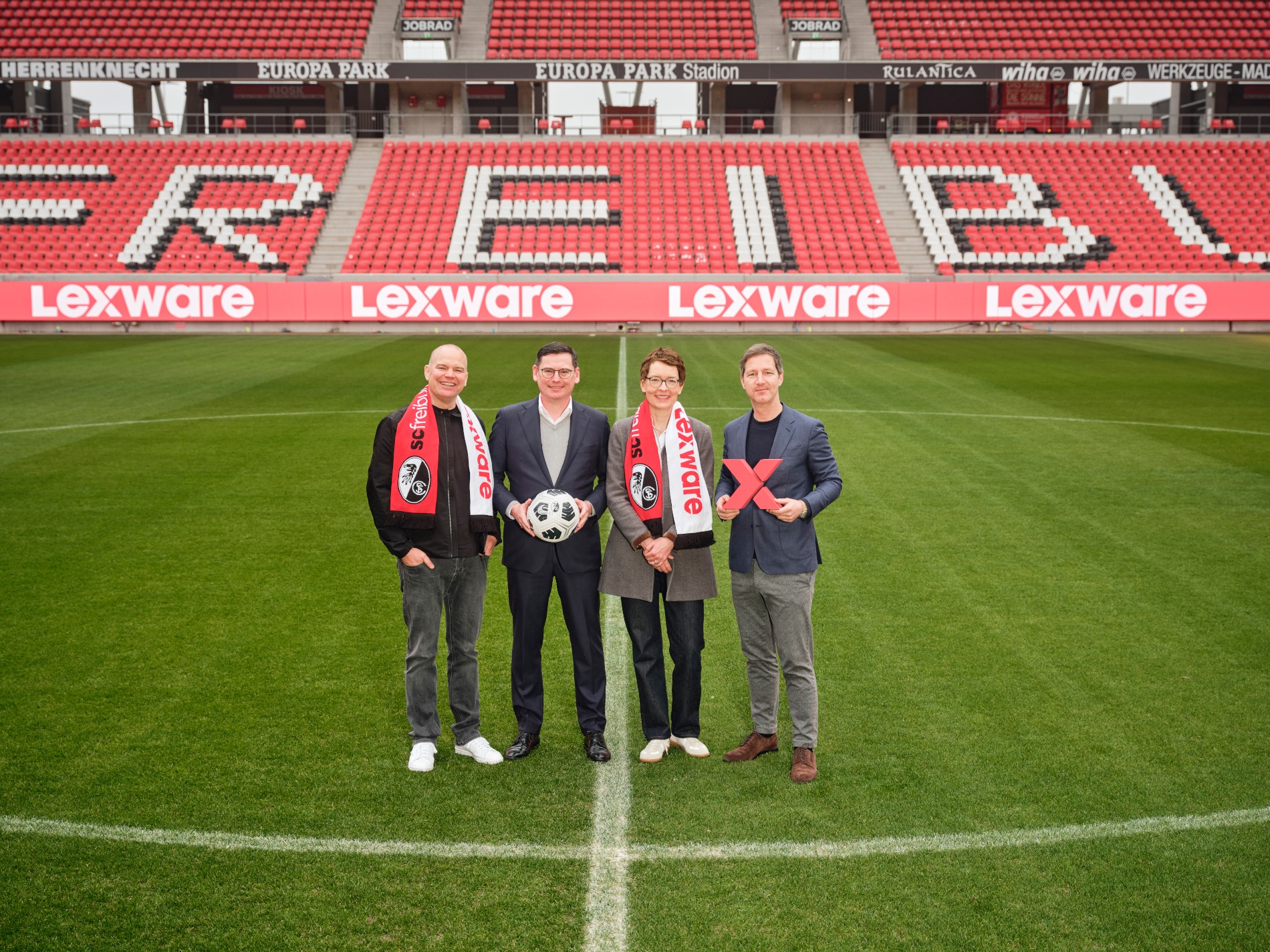 Christian Steiger, Oliver Leki, Birte Hackenjos und Jochen Saier im Europa-Park Stadion mit einer Lexware-LED-Bande im Hintergrund