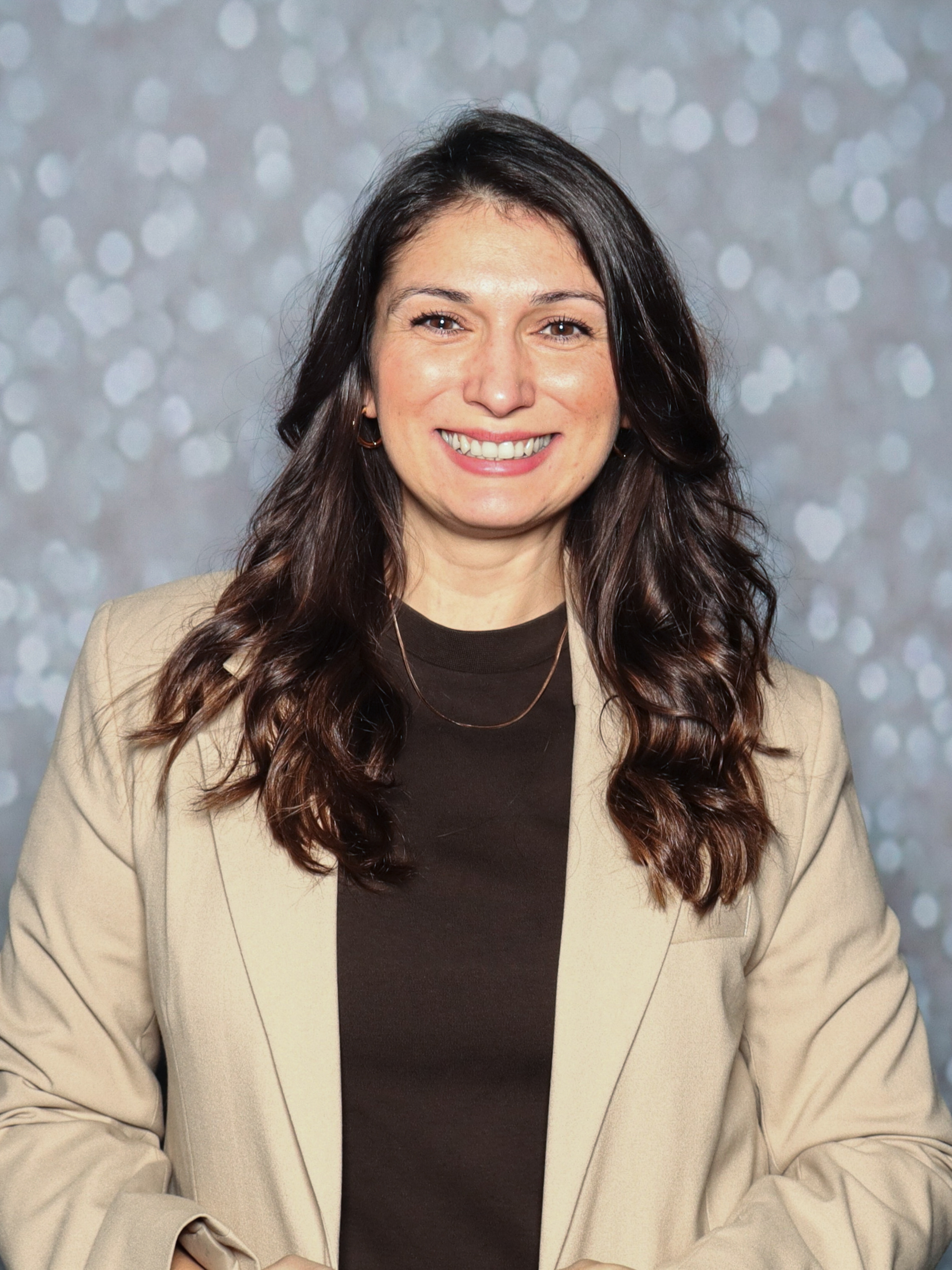 Yasmin Thon steht vor einem unscharfen Hintergrund und lächelt in die Kamera.