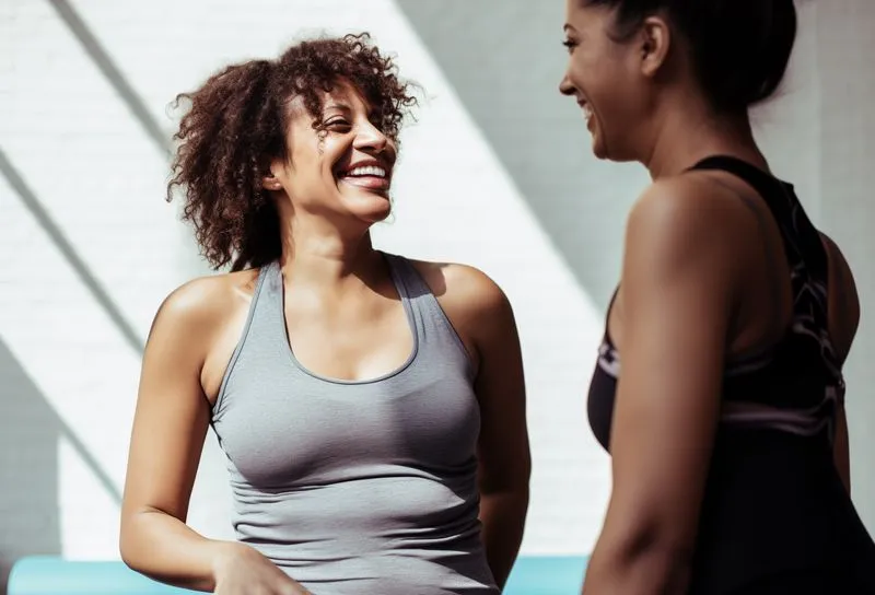 Two women talking to each other after a workout.