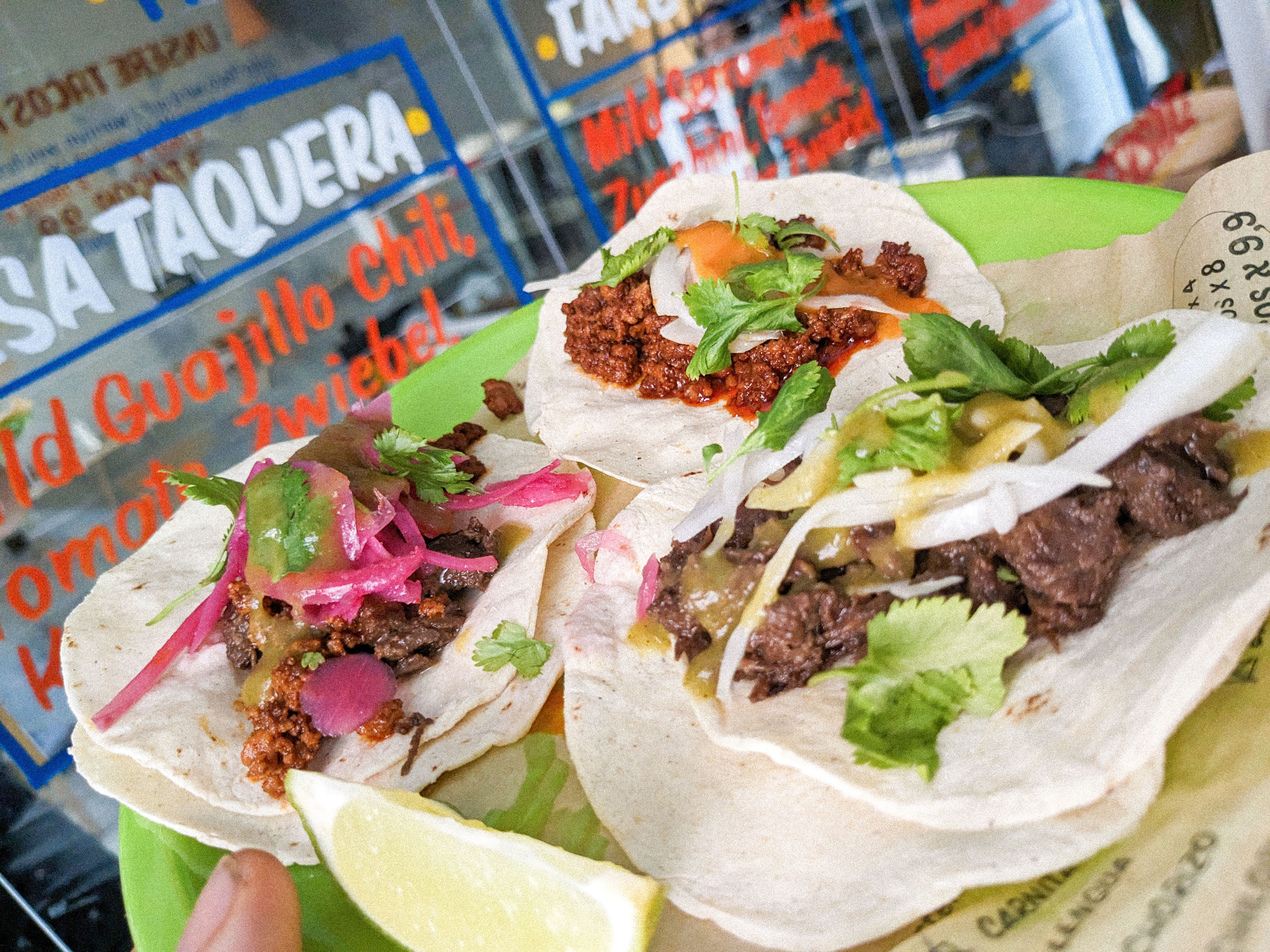 Fresh tacos being held in front of a taqueria window