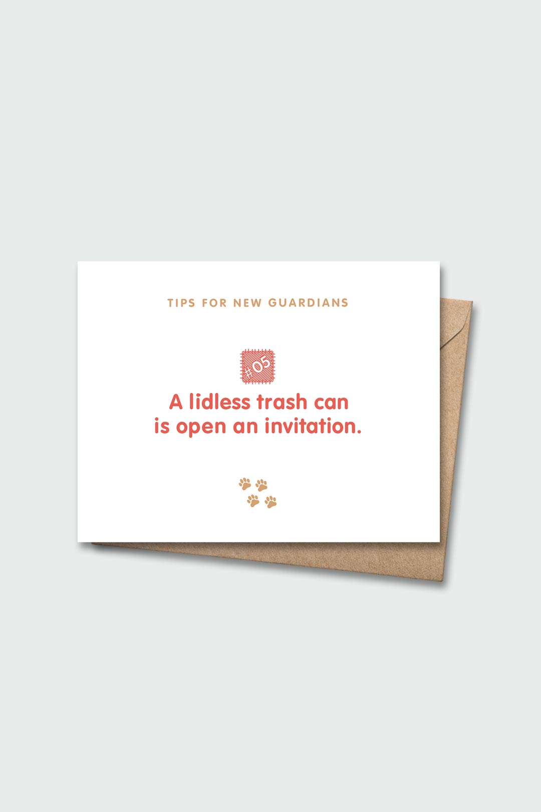 Letterpressed greeting card with wooden block and paw prints illustrations, the words "tips for new guardians: a lidless trash can is an open invitation" on white background, and taupe envelope