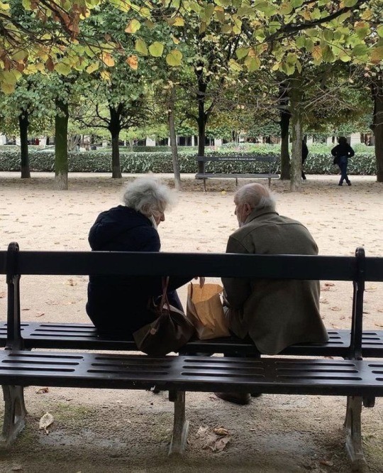 Two people on a park bench talking.