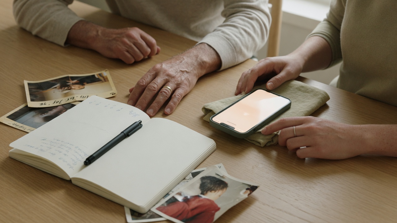 Private family moment. Soft light. Journal, prints, and phone on the table.