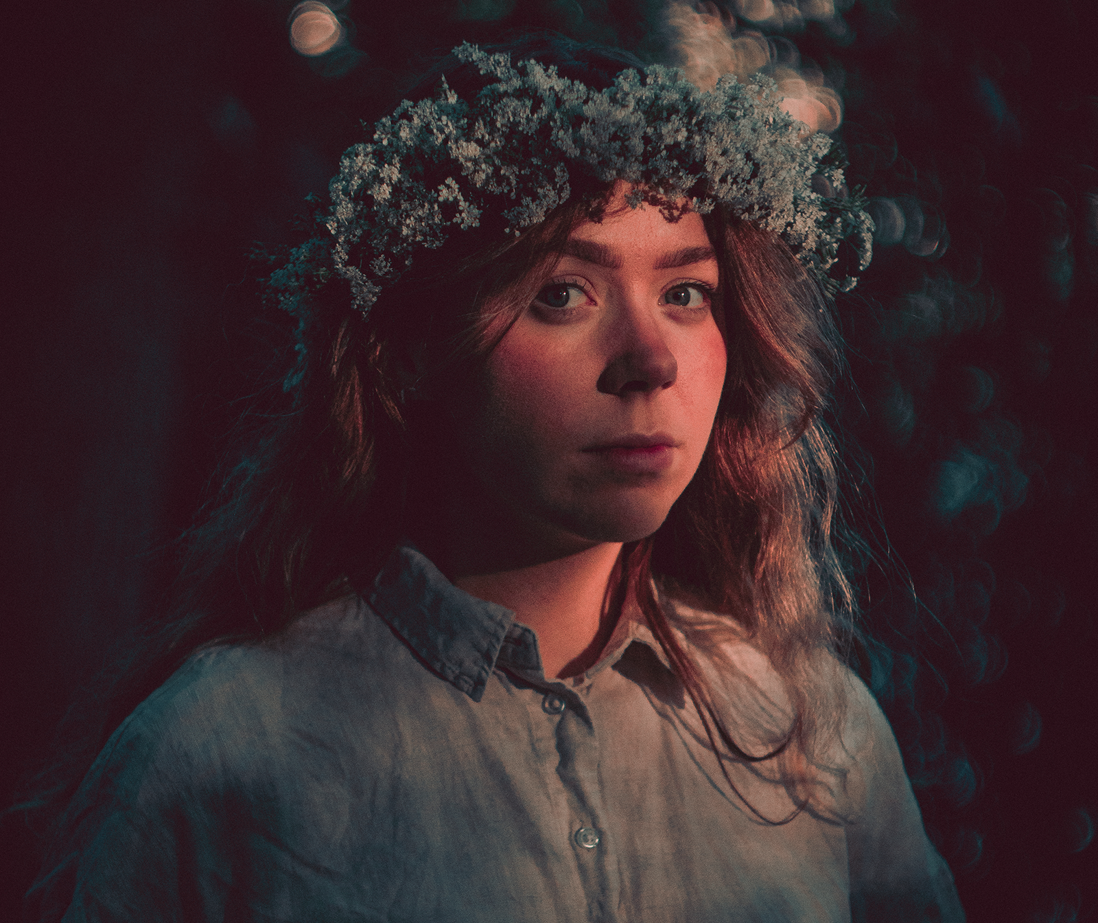 Portrait of girl with flowers in her hair in dramatic light