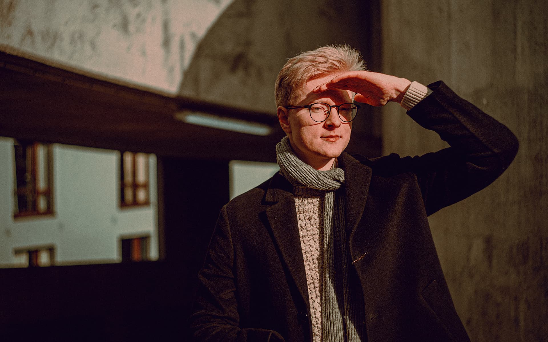 Portrait of man in a parking garage, shielding his face from the sun