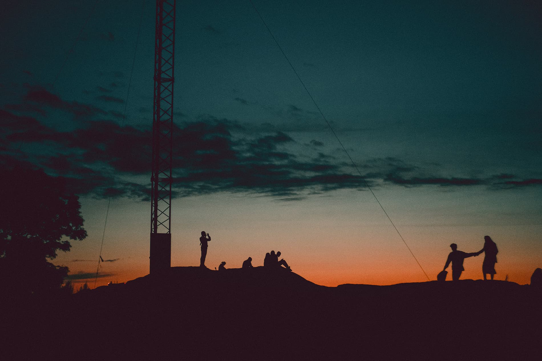 Backlit people sitting on a hill in sunset
