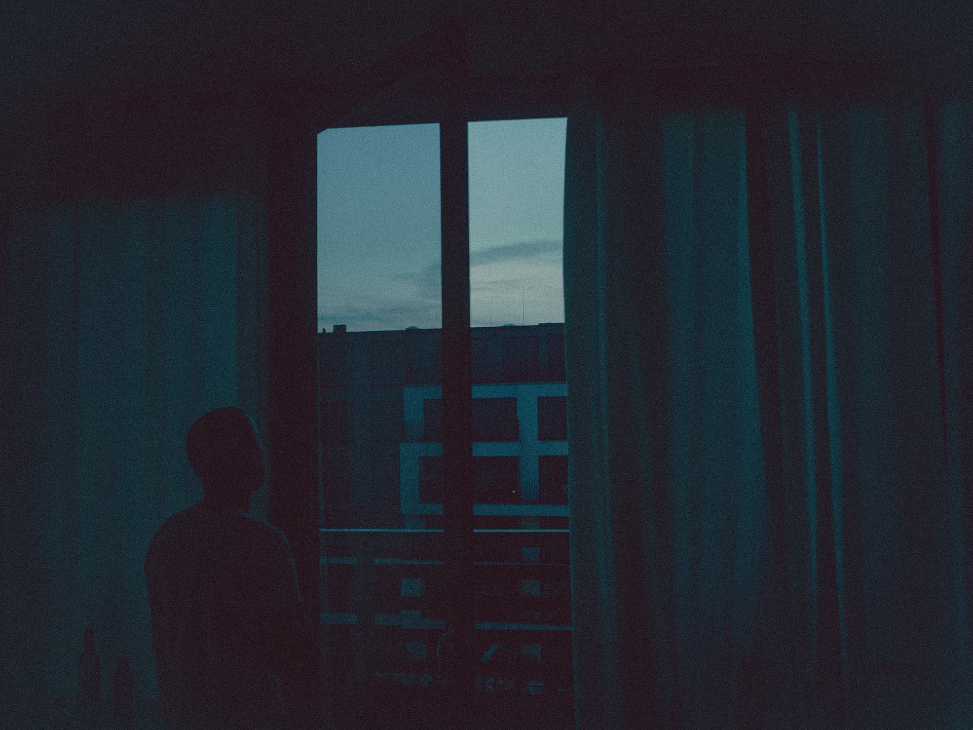 Backlit man starring out of window in the early morning
