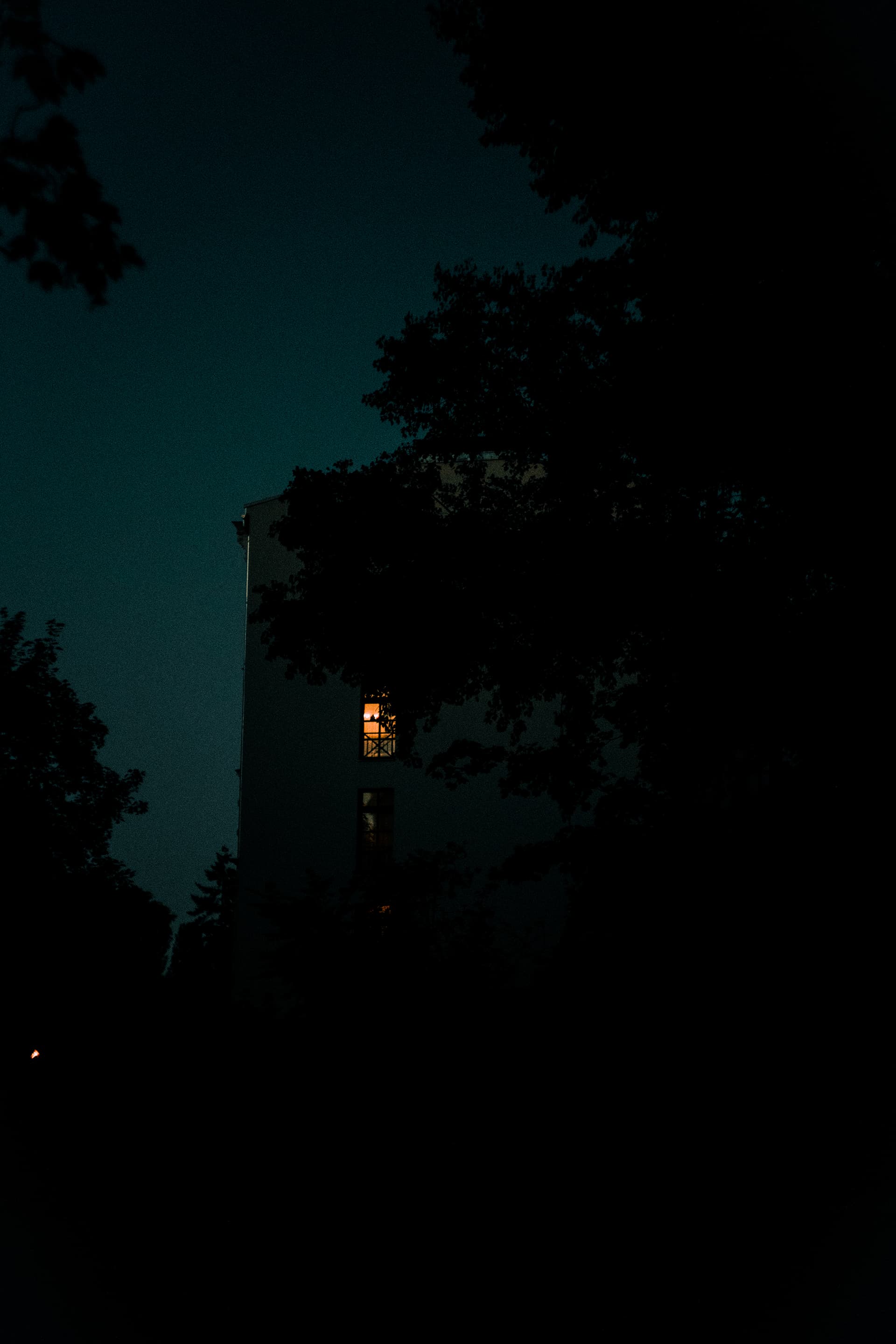 An apartment buiding with a lit up window in the night