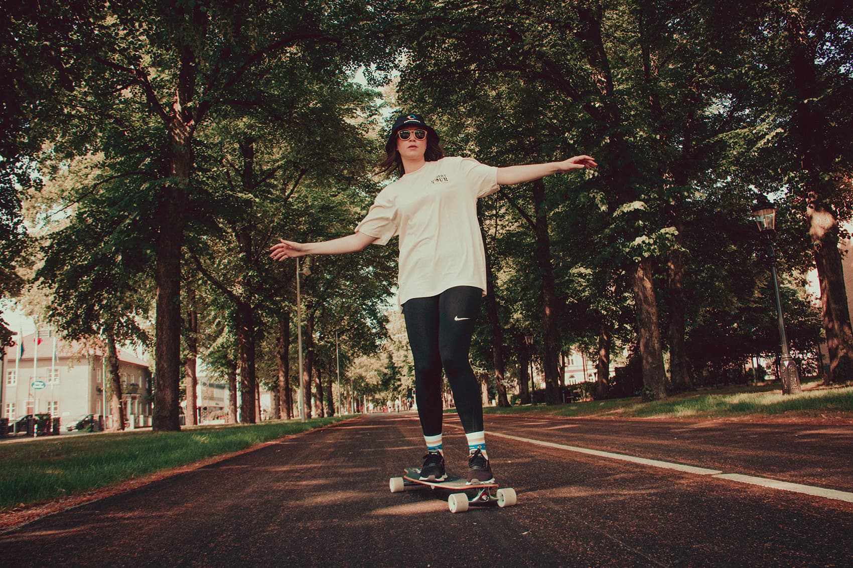 Woman in sunglasses and bucket hat skating on a longboard