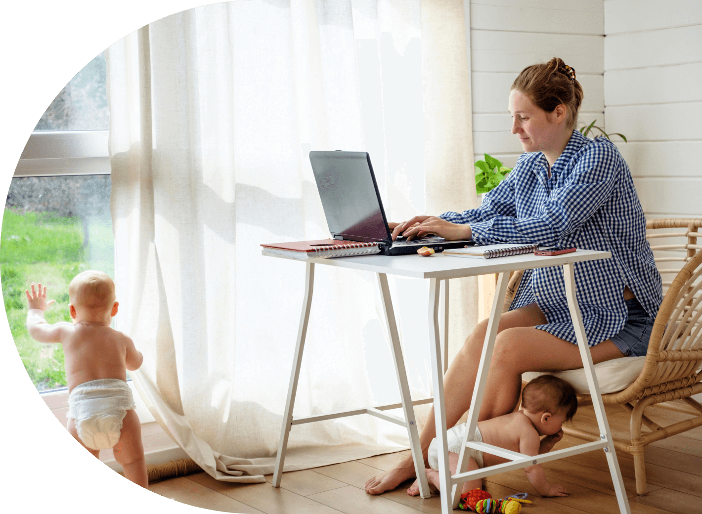 Image of a mother working while here toddlers play around her feet