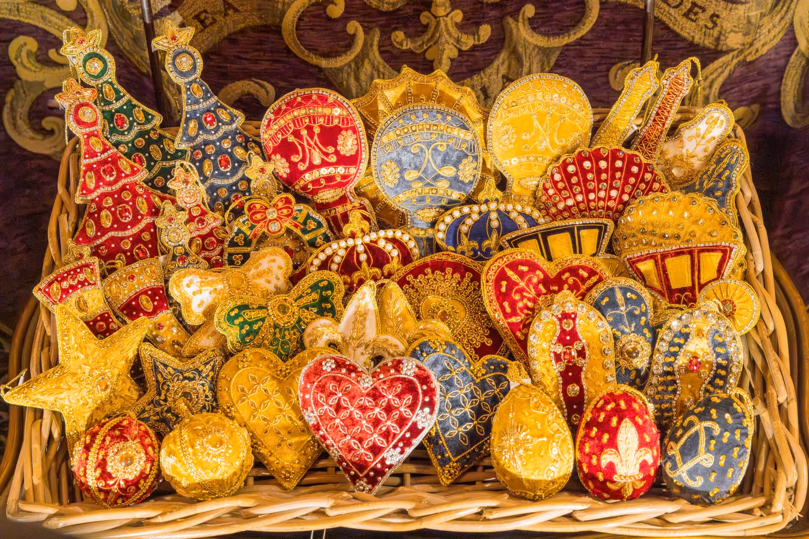 Panier rempli d'ornements brodés colorés et dorés en formes de cœurs, étoiles, arbres de Noël, éventails et plus.