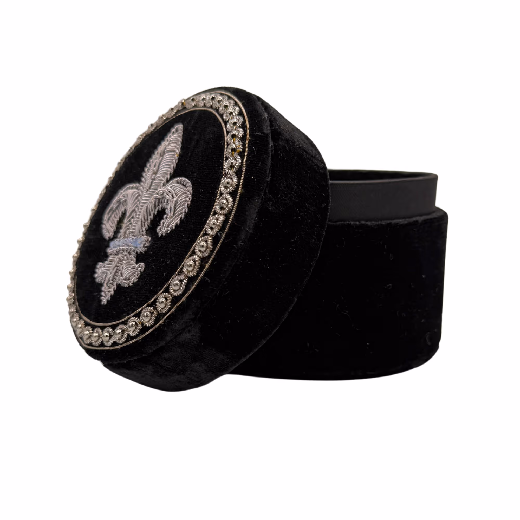 Boîte ronde noire en velours avec un couvercle brodé d'une fleur de lys argentée.