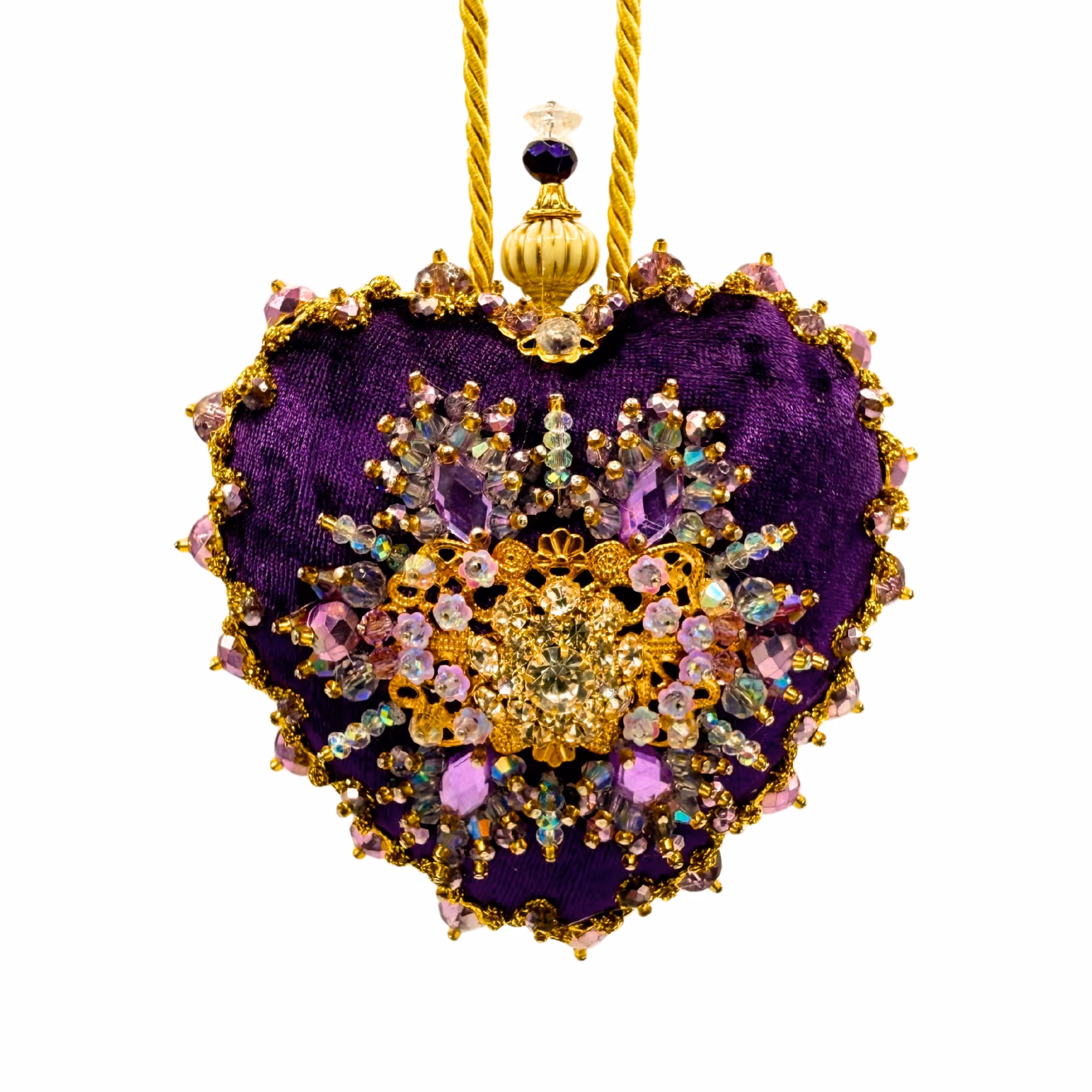 Cœur violet orné de bijoux et perles dorées suspendu par une corde dorée.