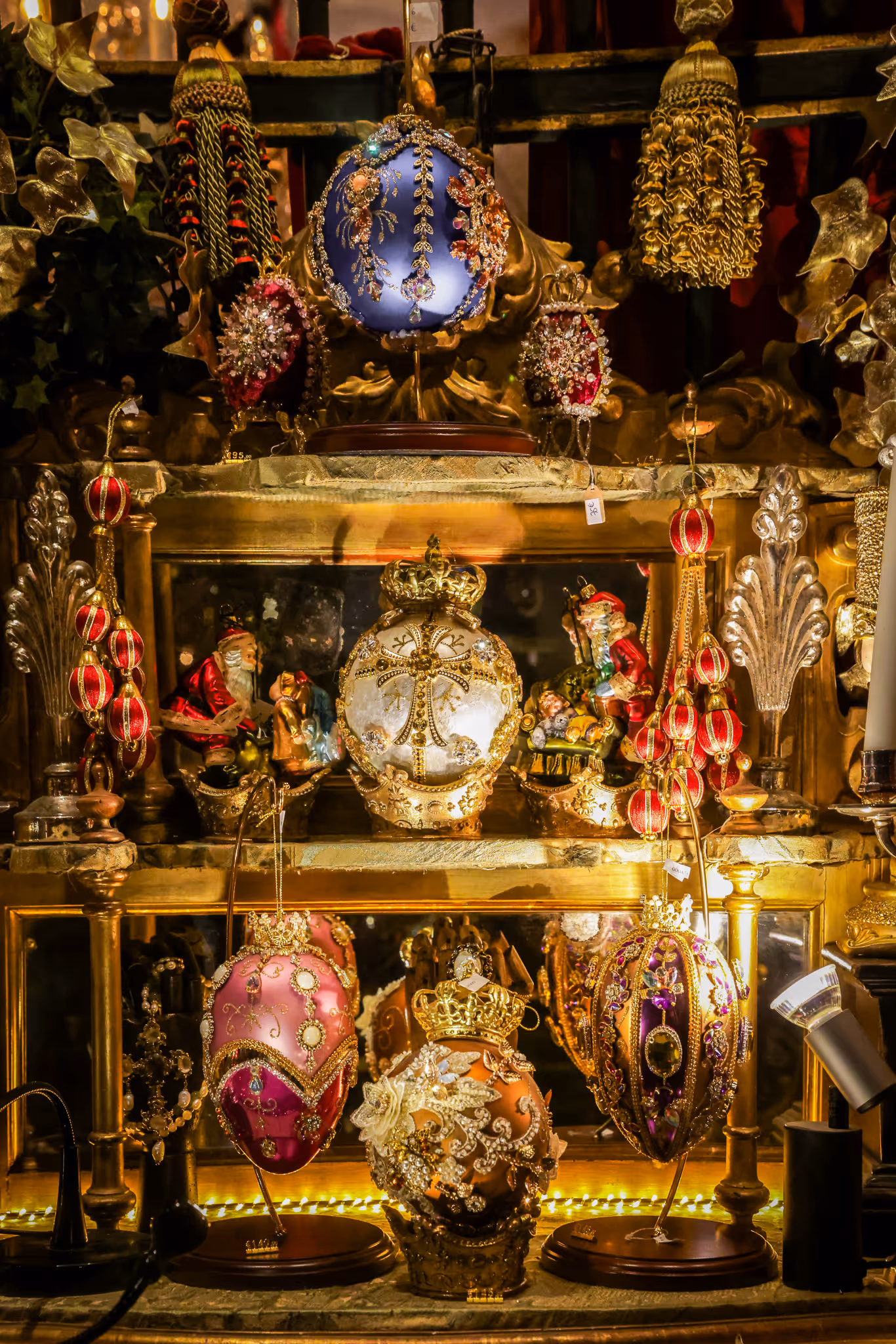 Ornements de Noël décoratifs et riches en or exposés avec des figurines festives sur une étagère.
