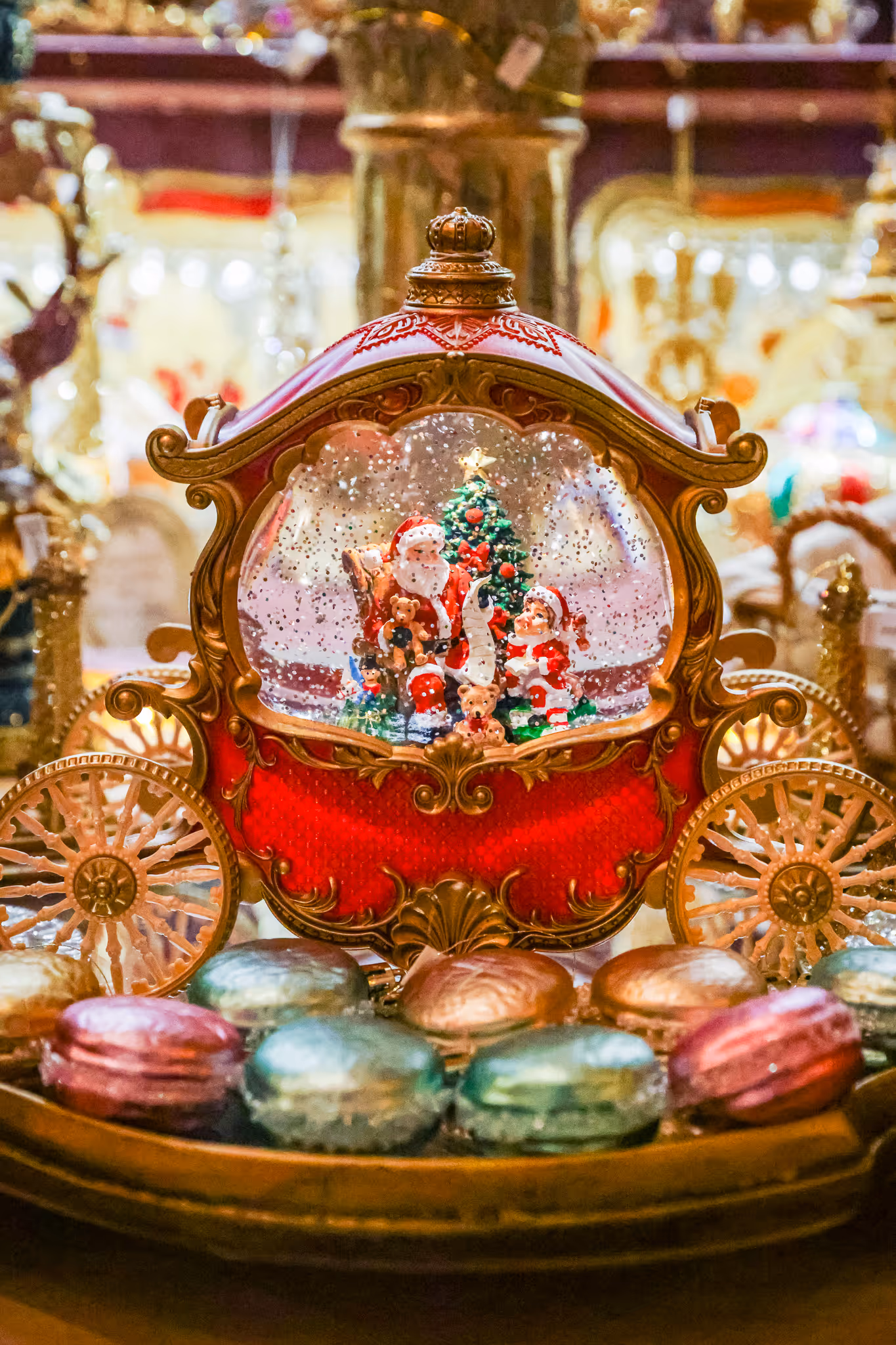 Globe de neige décoratif avec Père Noël, enfant, sapin et ours dans un chariot orné de rouge et or.