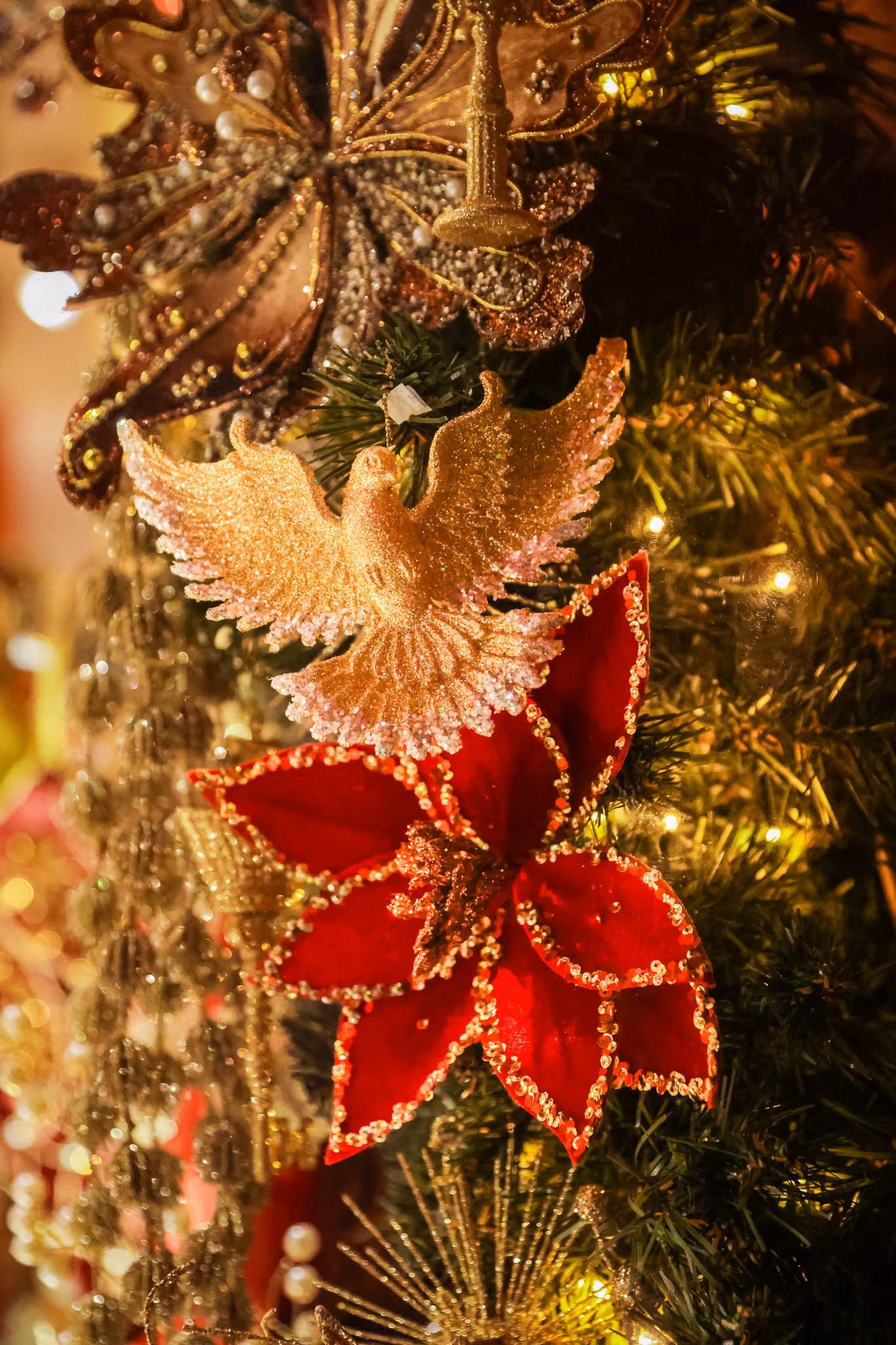 Ornement d'arbre de Noël avec une colombe dorée et une fleur rouge scintillante.