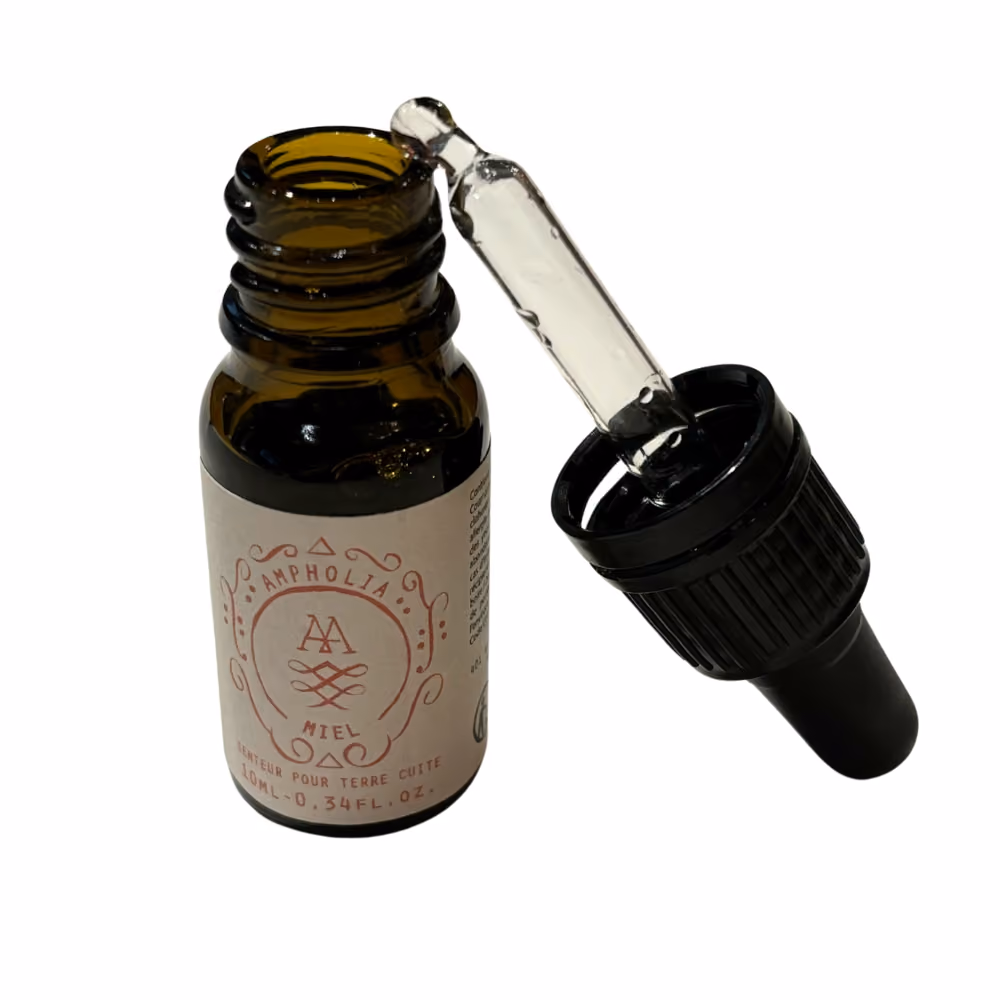 Petit flacon brun avec une pipette noire détachable, étiquette indiquant "Ampholia Miel".