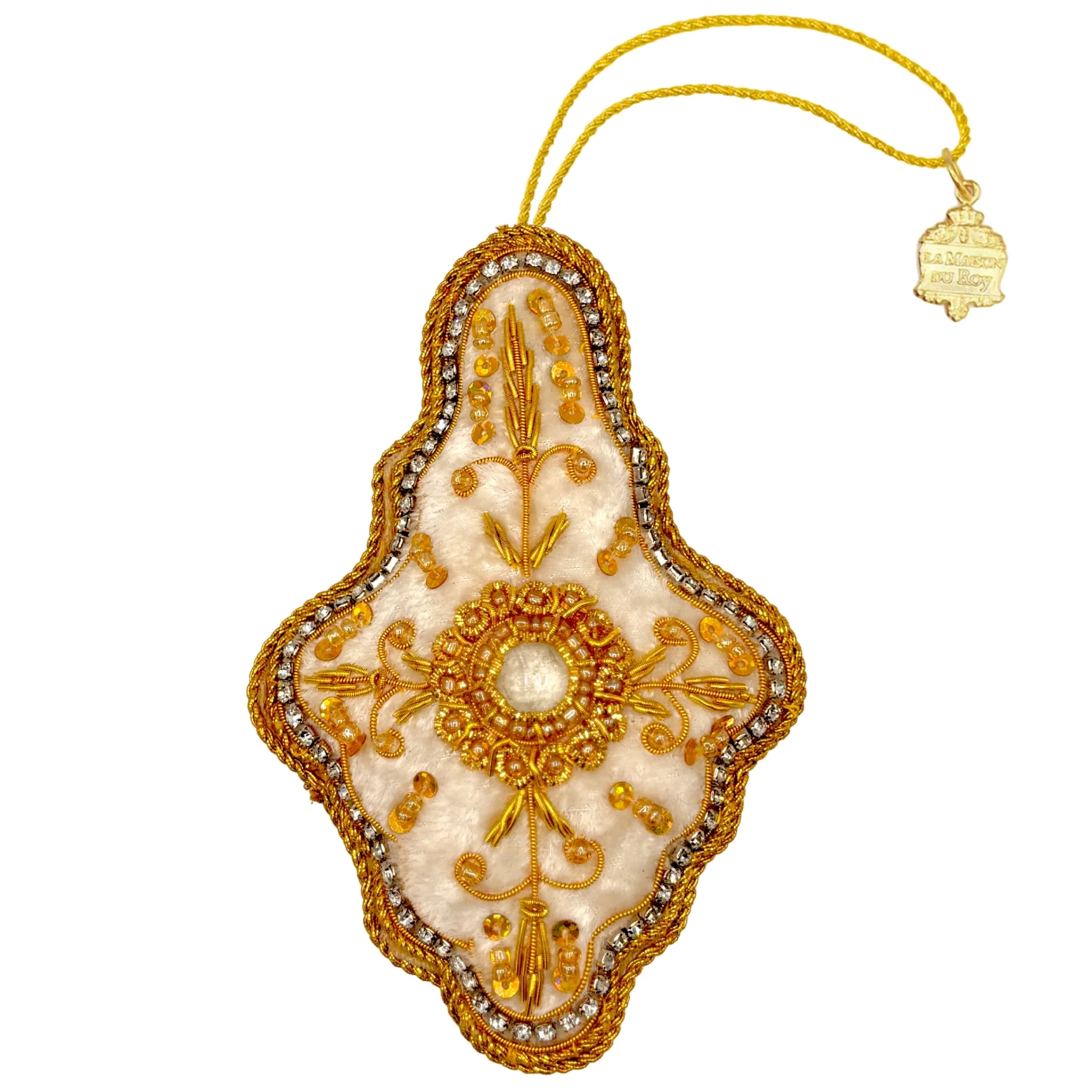 Élément décoratif brodé de forme losange avec centre circulaire, orné de fils dorés, perles dorées, et strass sur fond en tissu crème, suspendu à un cordon jaune avec une petite étiquette métallique gravée "LA MAISON DU ROY".