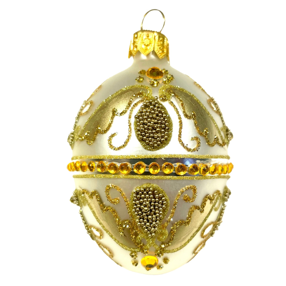 Œuf en verre soufflé blanc décoré d'or, strass jaunes et perles sur fond blanc