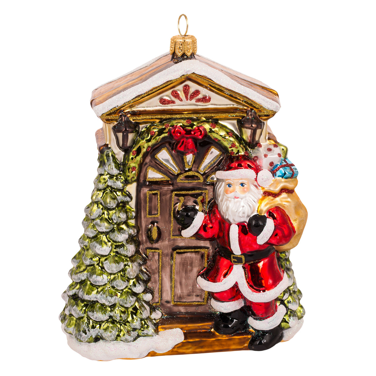 Père Noël en verre soufflé rouge devant une maison décorée et un sapin enneigé