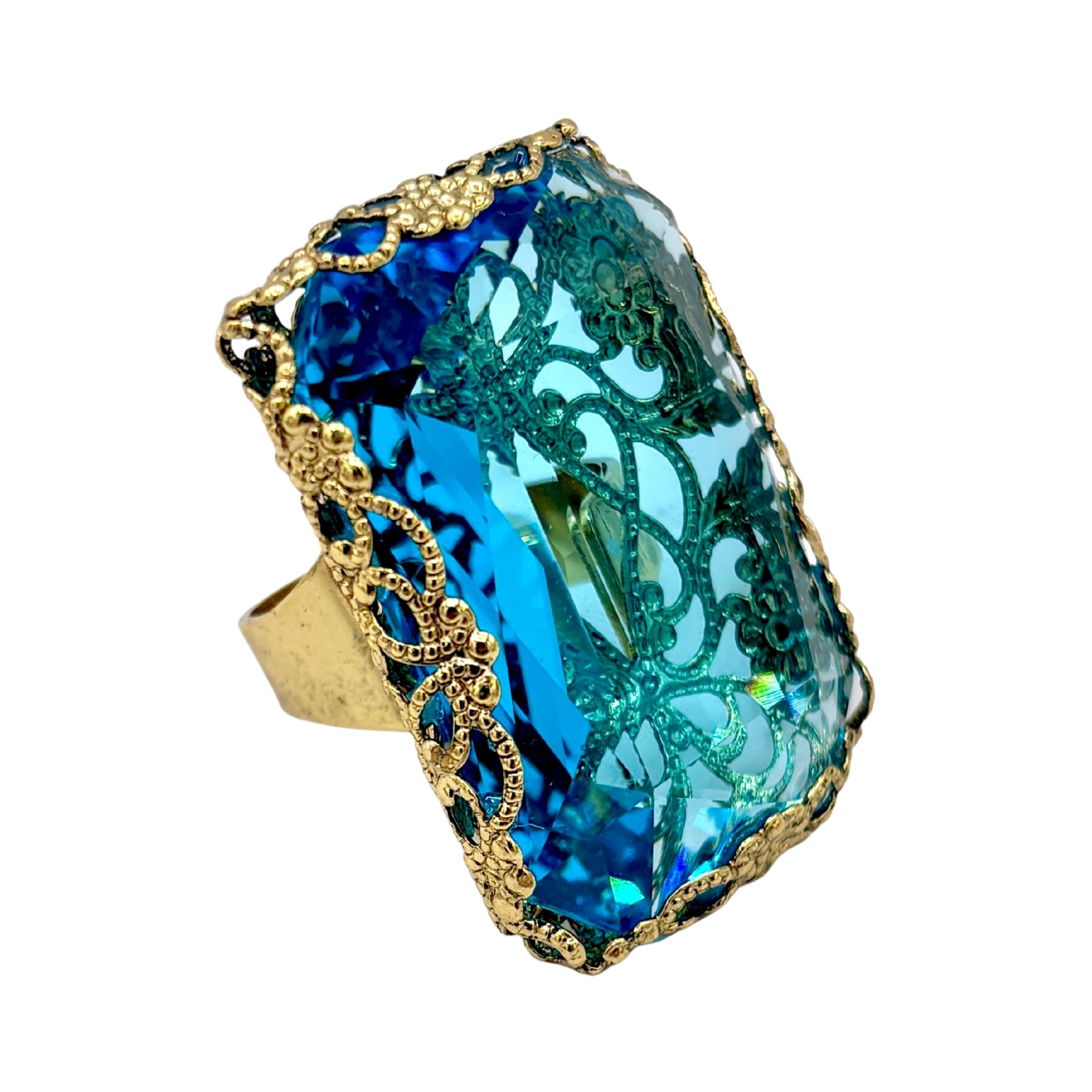 Bague ornée d’un grand cristal bleu facetté, monture dorée travaillée aux motifs arabesques vintage