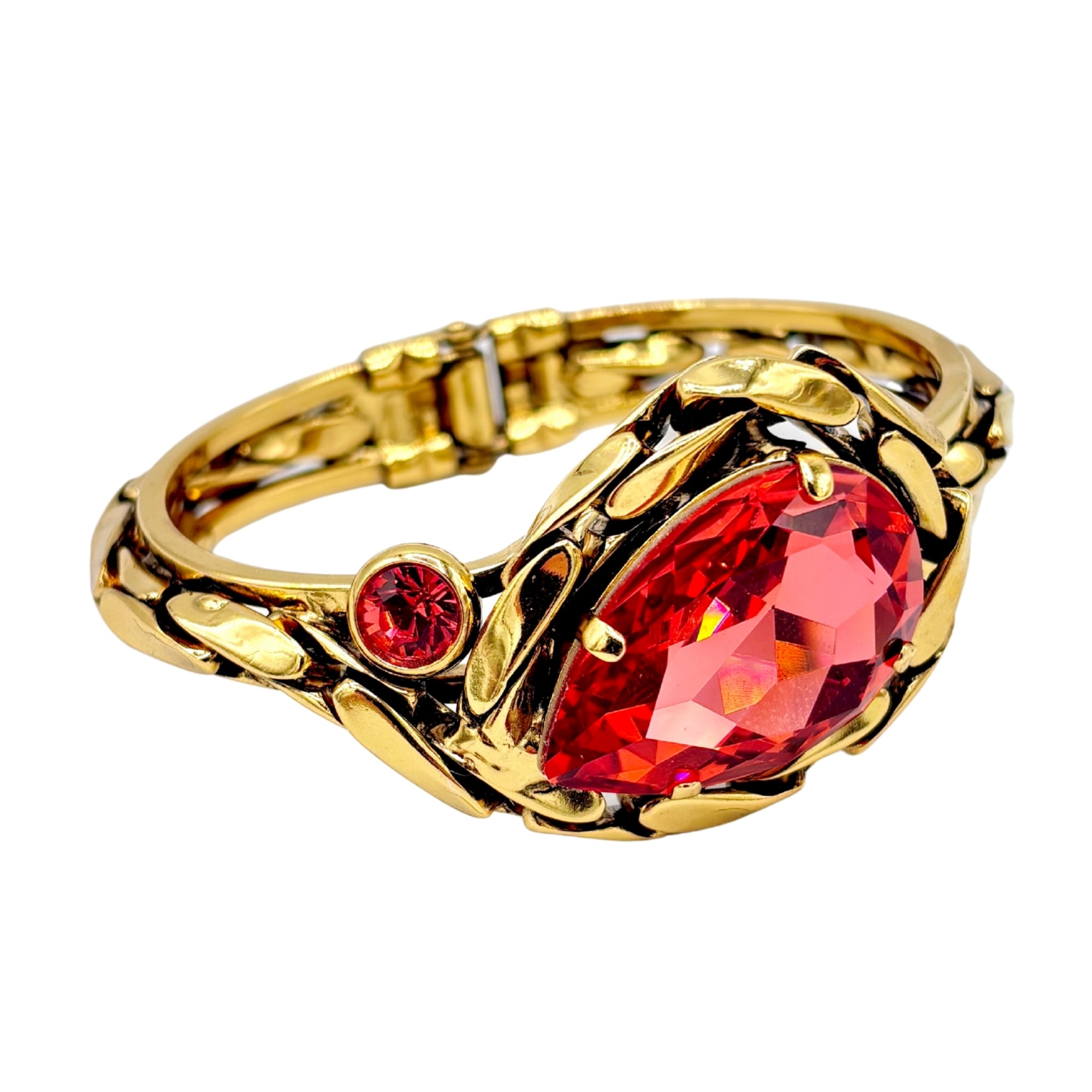 Bracelet en laiton doré orné d’un grand cristal rouge facetté et d’un petit cristal, motifs feuillage ajourés