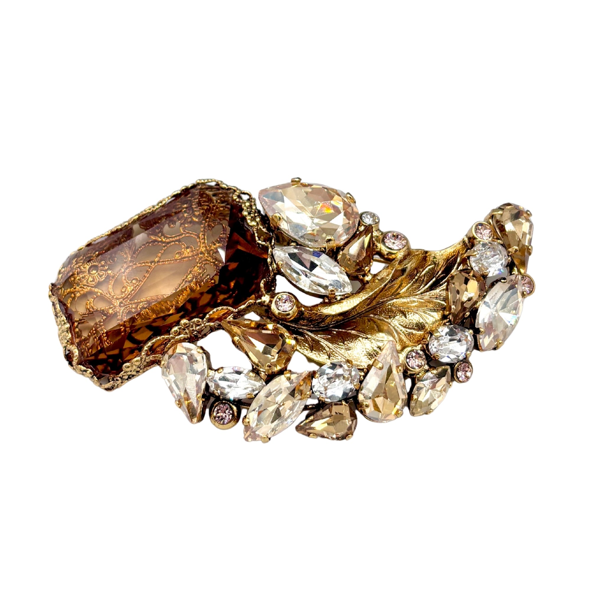 Broche en laiton doré ornée d’un grand cristal ambré et de pierres facettées claires, motif feuillage